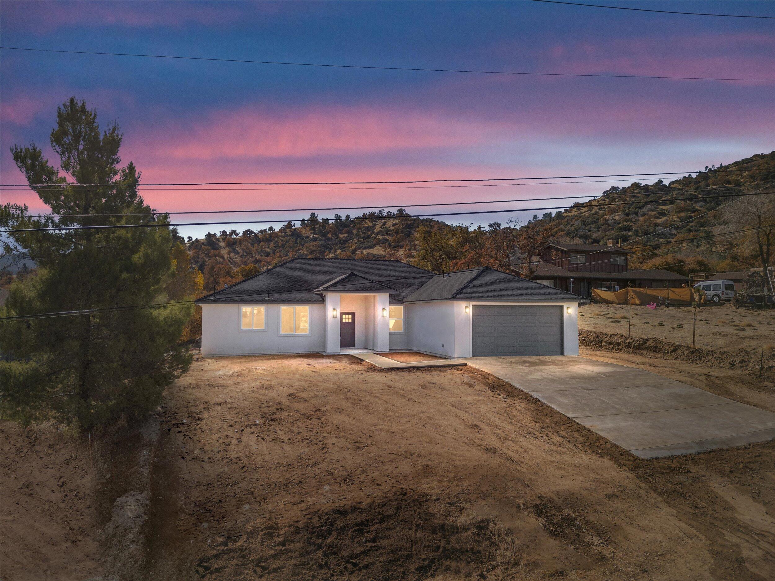 a front view of a house with a yard and mountain view