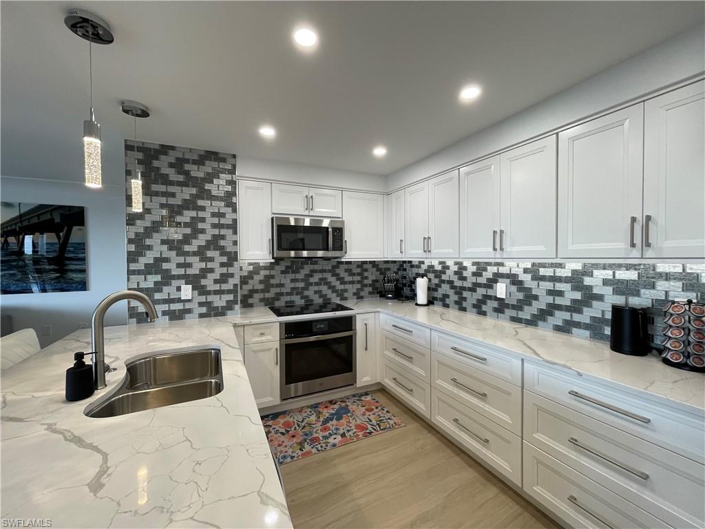 a kitchen with kitchen island granite countertop a sink and white cabinets