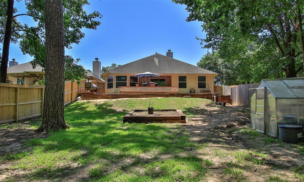 Spacious backyard with mature trees, a large deck for entertaining, all enclosed by a privacy fence.