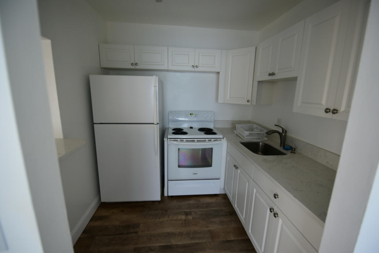 a kitchen with a refrigerator a stove top oven and cabinets