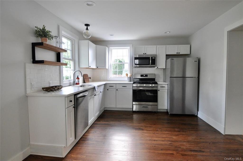 a kitchen with a sink cabinets stainless steel appliances and a window