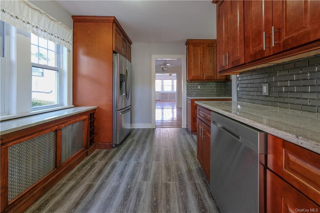 a kitchen with granite countertop wooden floors wooden cabinets and stainless steel appliances