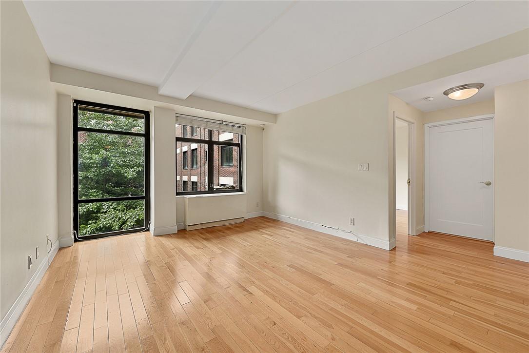 Empty room featuring light wood-type flooring and beam ceiling