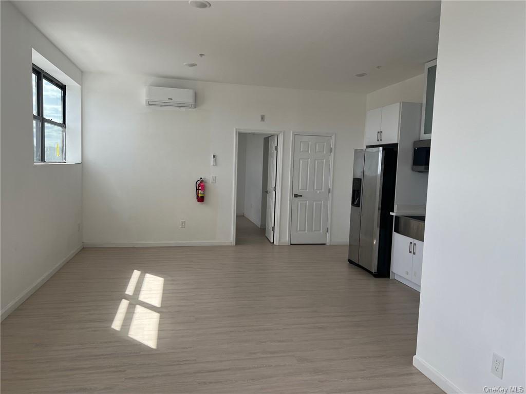 a view of empty room with window and refrigerator