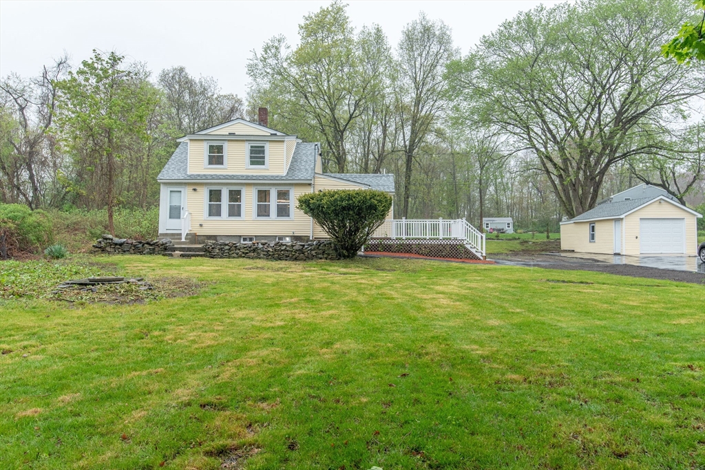 a front view of house with yard and trees in the background