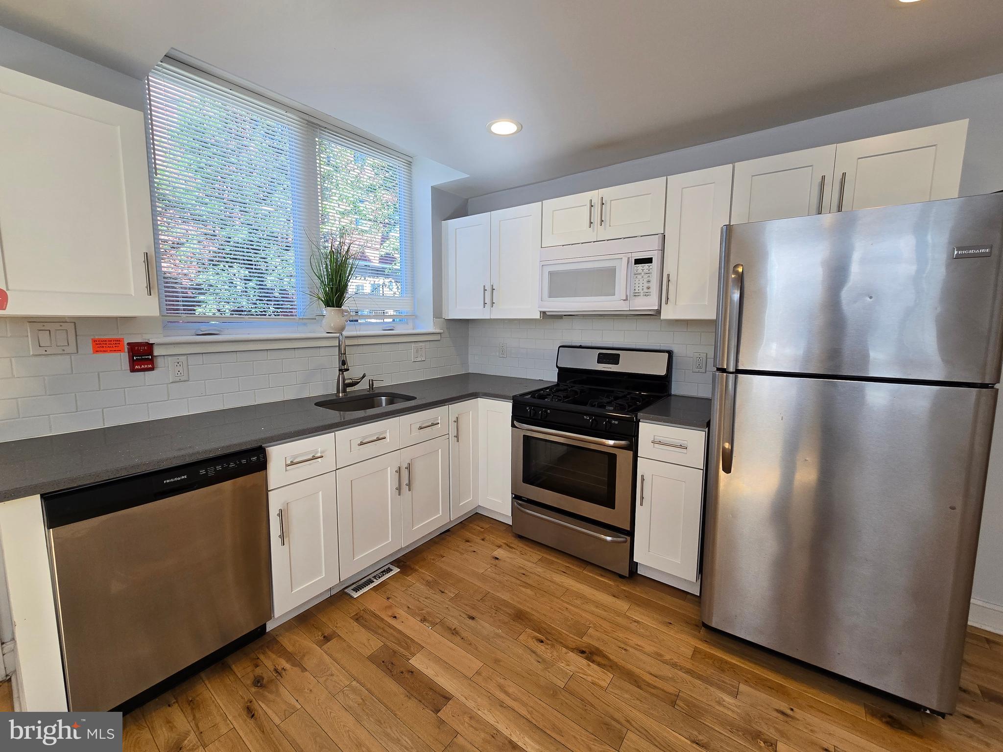 a kitchen with granite countertop a refrigerator a sink and white cabinets