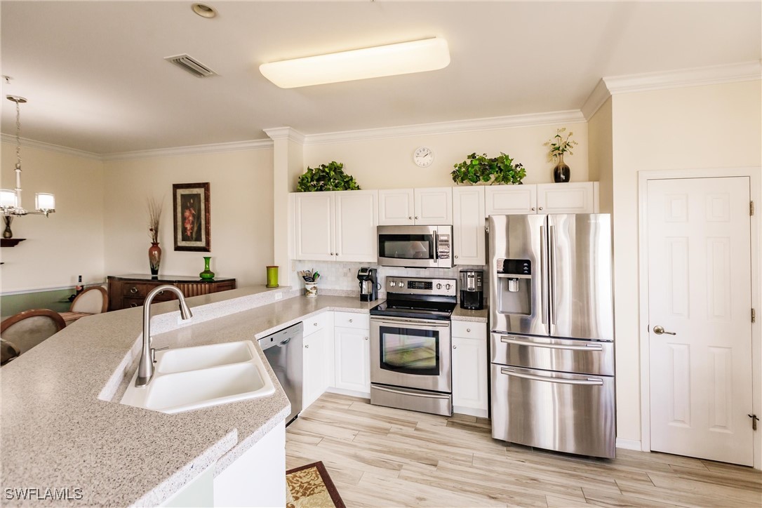 a kitchen with granite countertop a refrigerator a stove and a sink with wooden floor