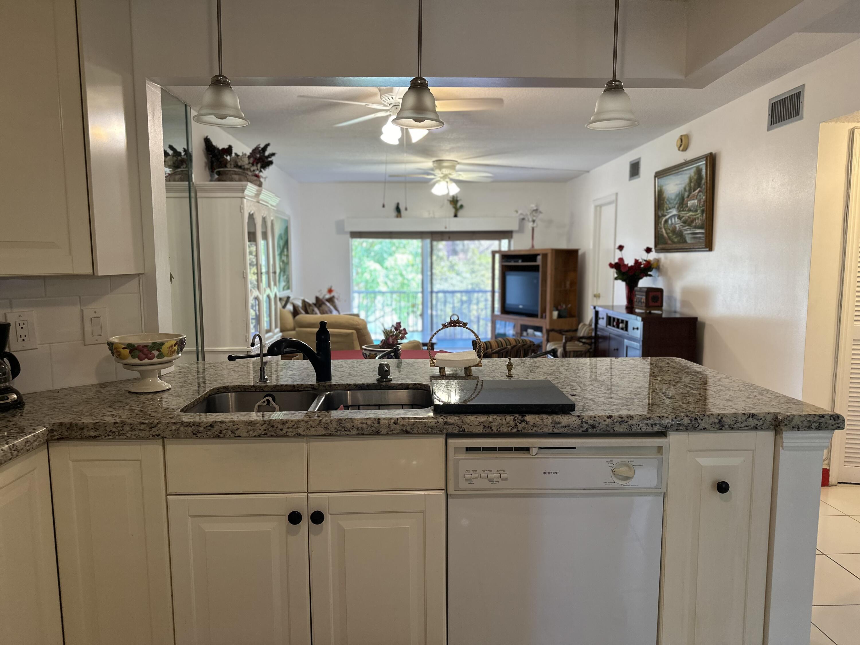 a kitchen with kitchen island granite countertop a sink cabinets and stainless steel appliances