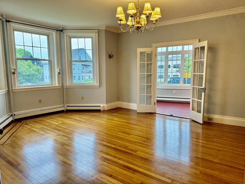 a view of an empty room with a window and wooden floor