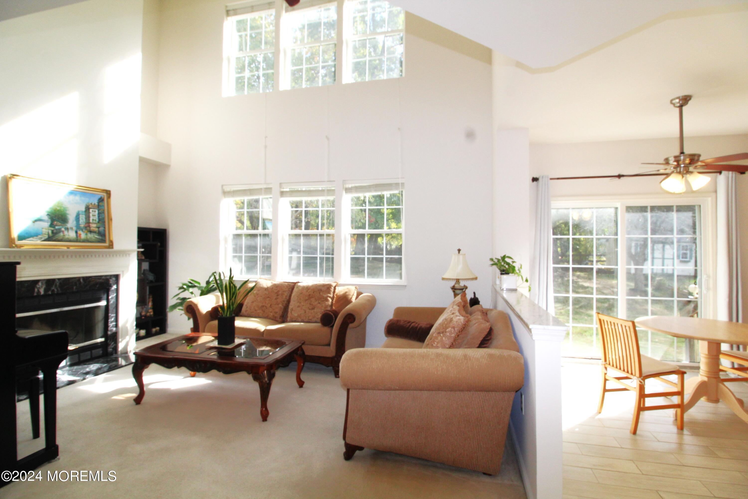 a living room with furniture a fireplace and floor to ceiling windows