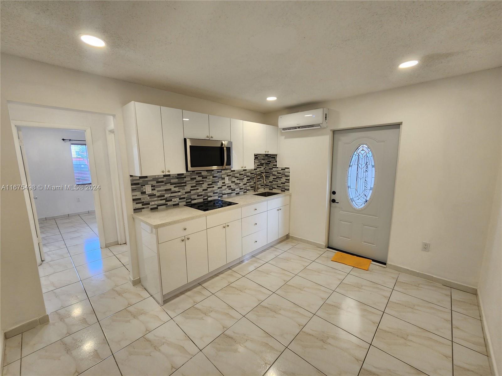 a kitchen with white cabinets and refrigerator