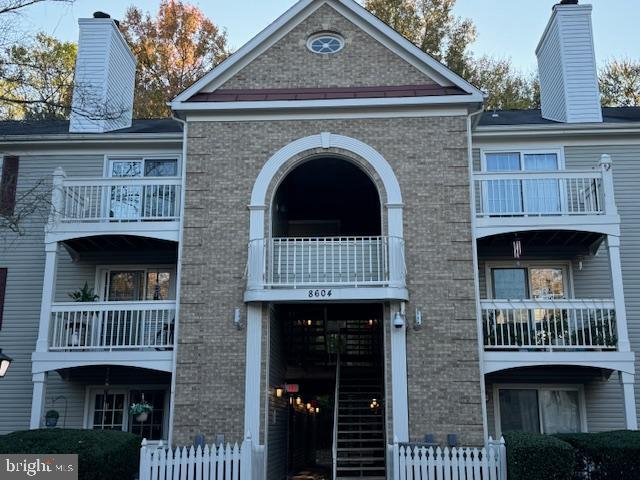 a view of a brick house with large windows and a deck