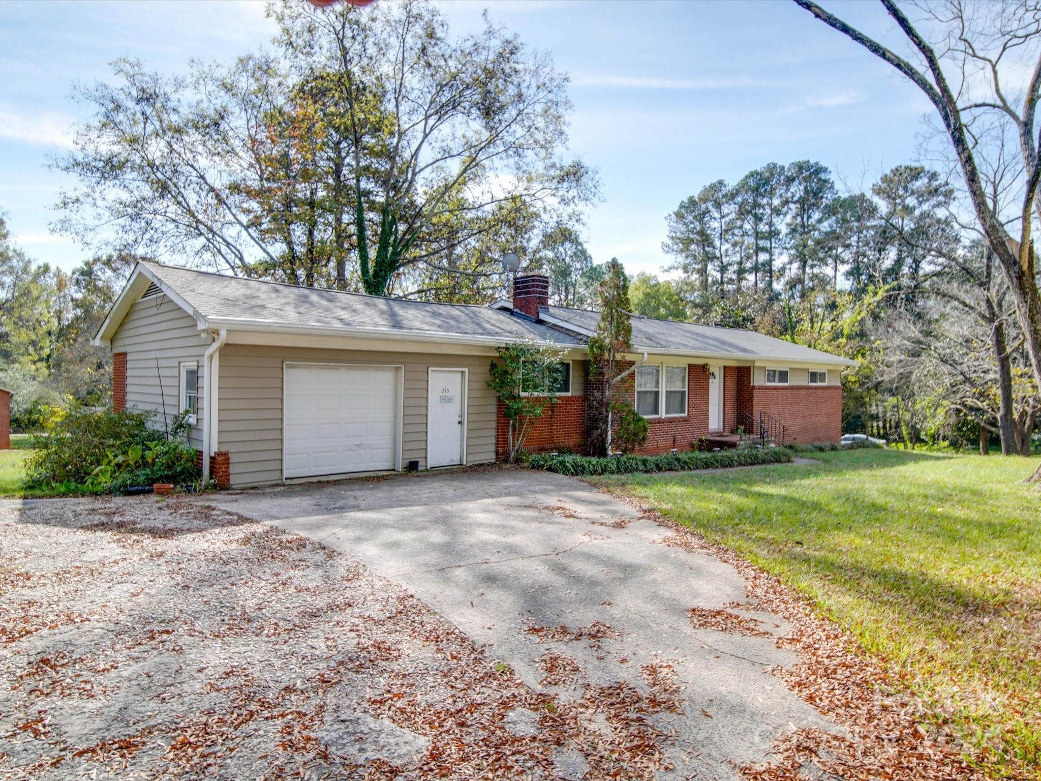 a view of a house with a yard and large trees