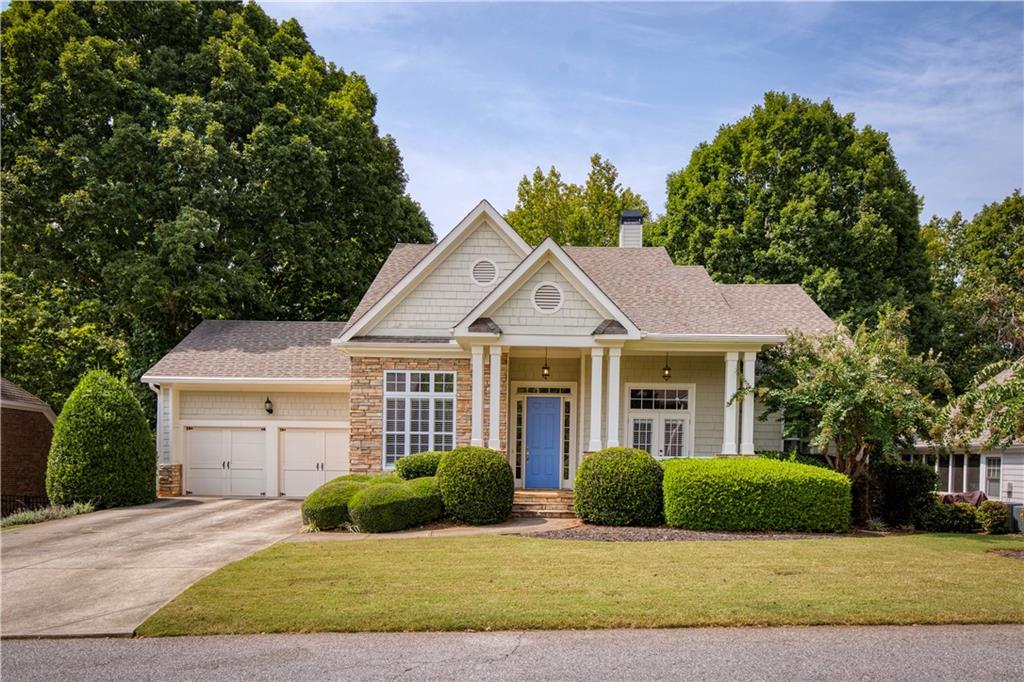 a view of a brick house next to a yard with potted plants and big trees