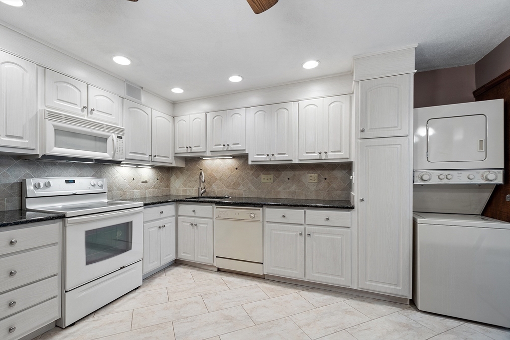 a kitchen with kitchen island granite countertop white cabinets stainless steel appliances and a sink