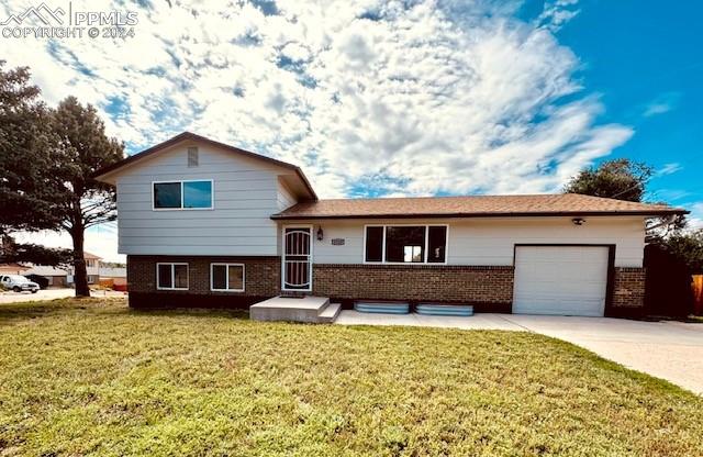 Split level home featuring a garage and a front lawn