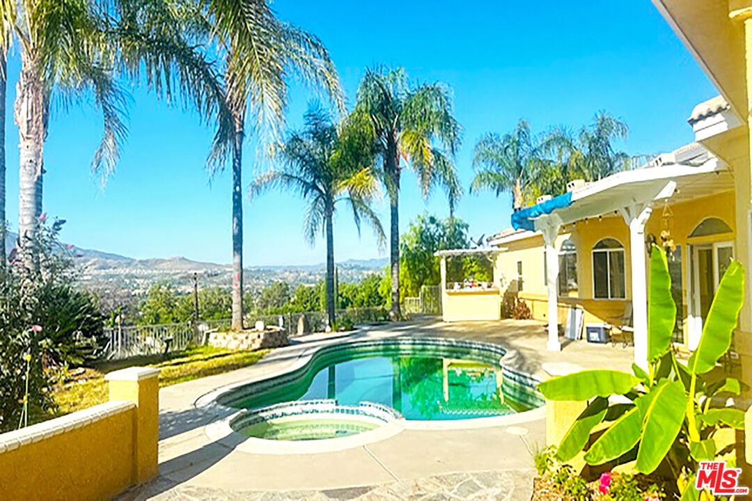 a view of a swimming pool with a lawn chairs under palm trees