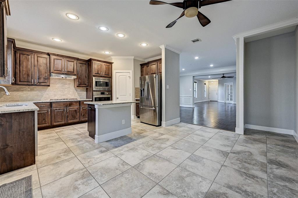 a large kitchen with stainless steel appliances granite countertop a refrigerator and a sink