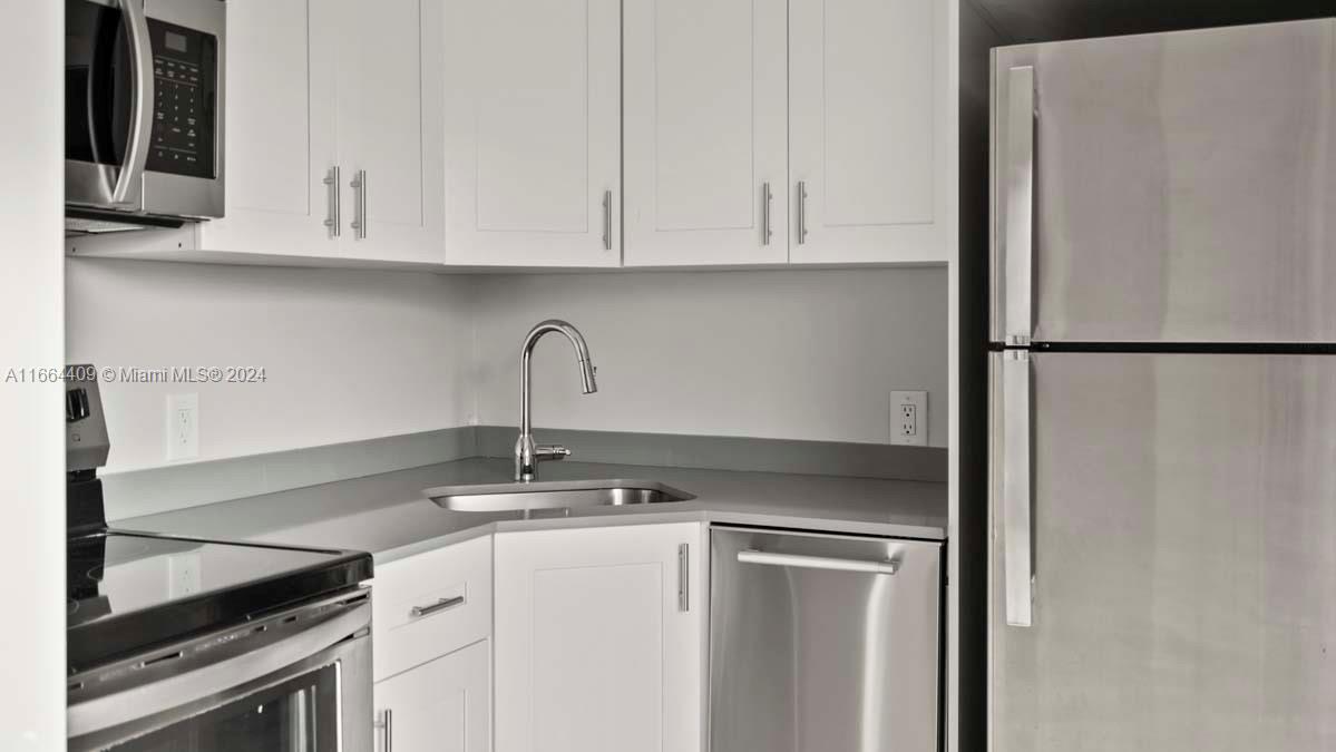 a kitchen with stainless steel appliances granite countertop white refrigerator stove and white cabinets