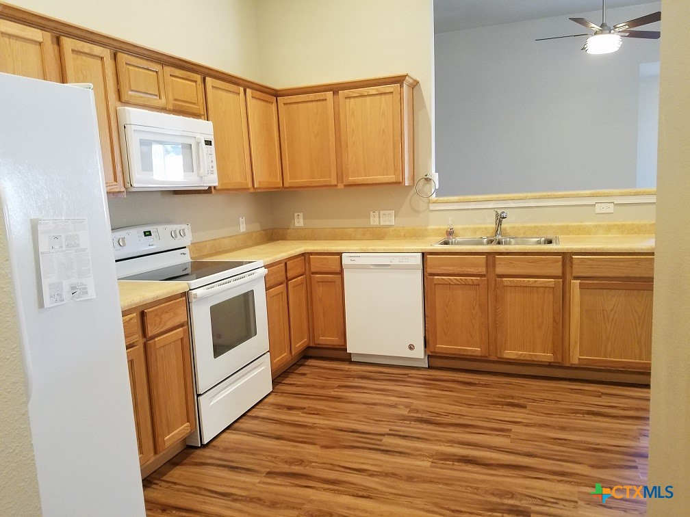 a kitchen with stainless steel appliances granite countertop a sink and cabinets with wooden floor