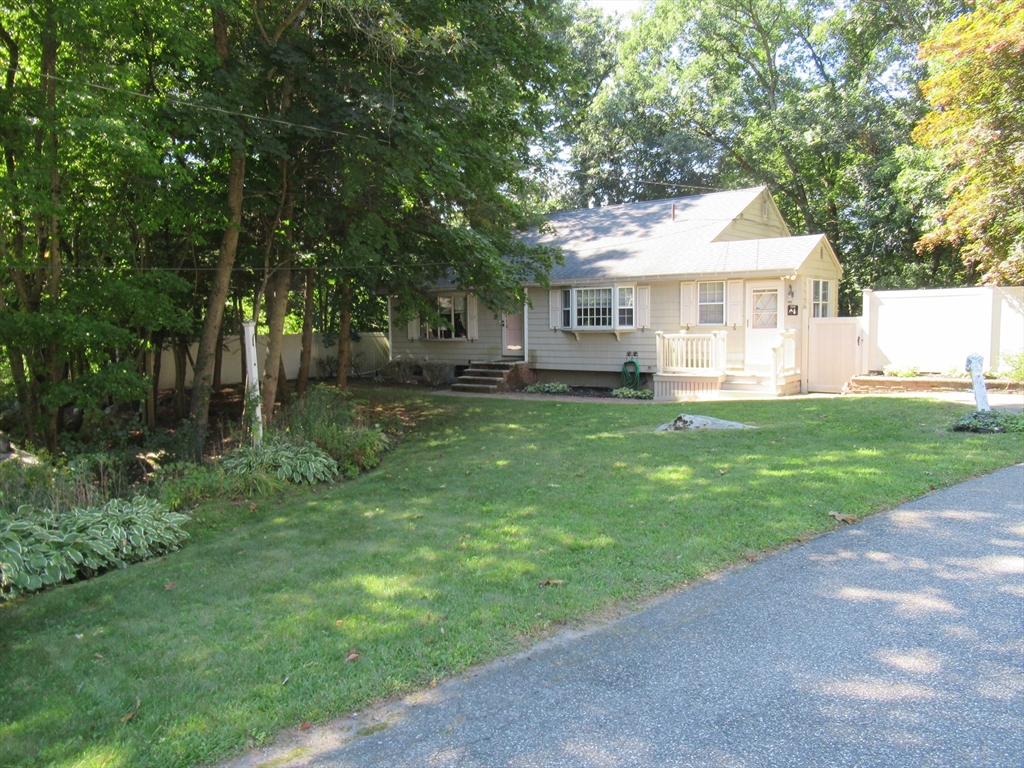 a front view of a house with a garden and trees