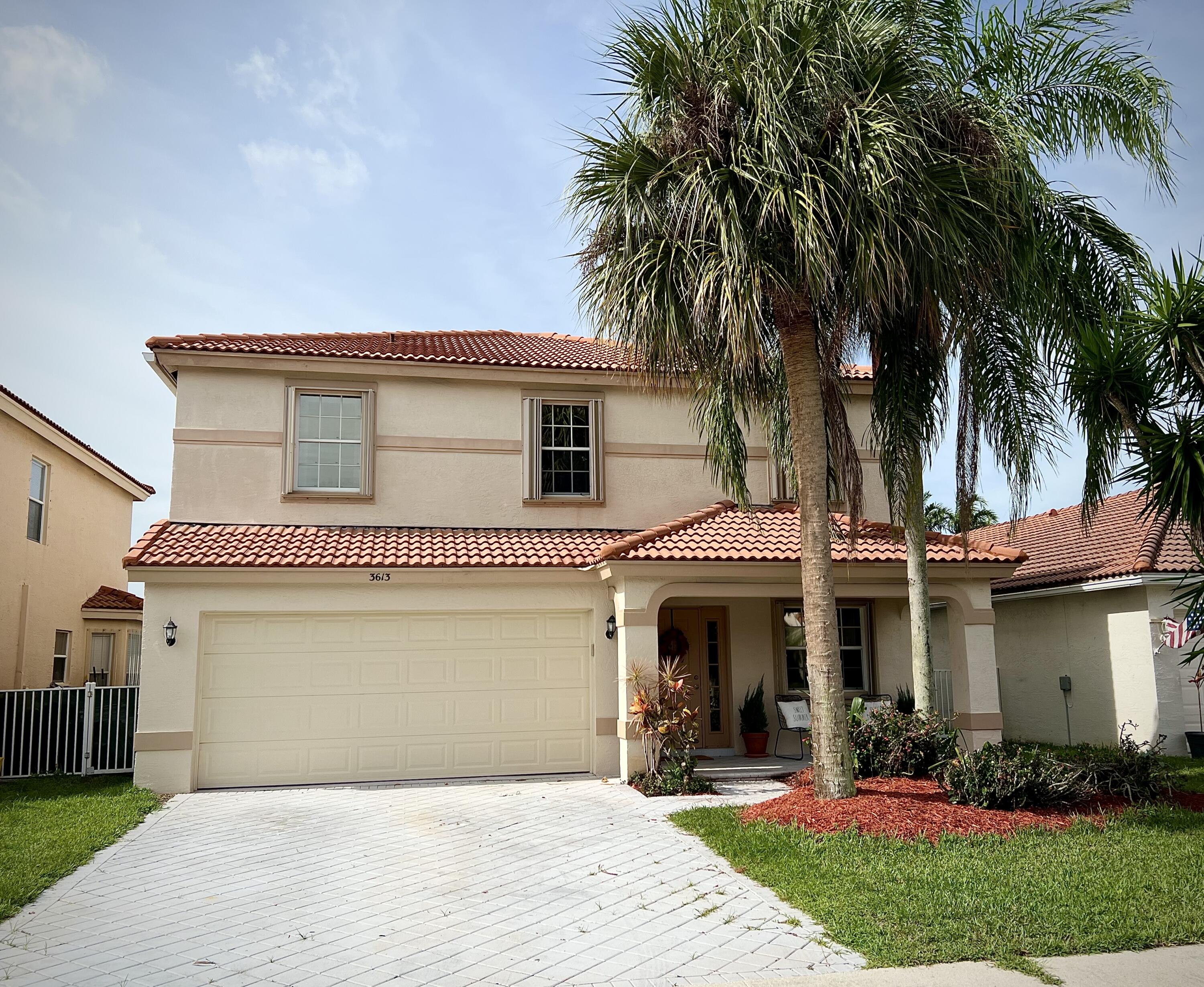 a front view of a house with a garden and palm trees