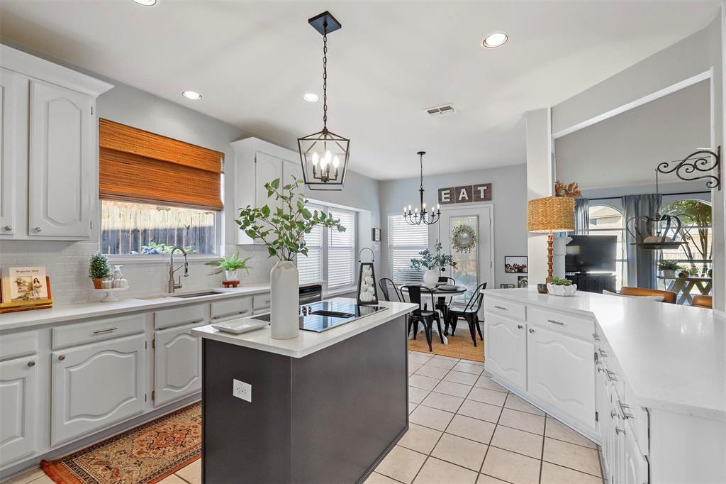 a large white kitchen with lots of counter space and chandelier