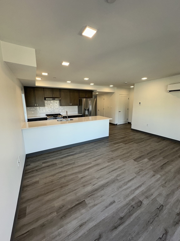 a view of kitchen and empty room with wooden floor