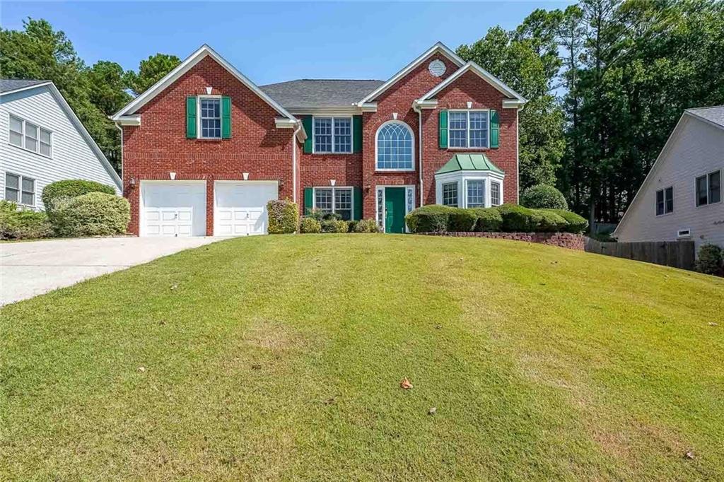 a front view of a house with yard and green space