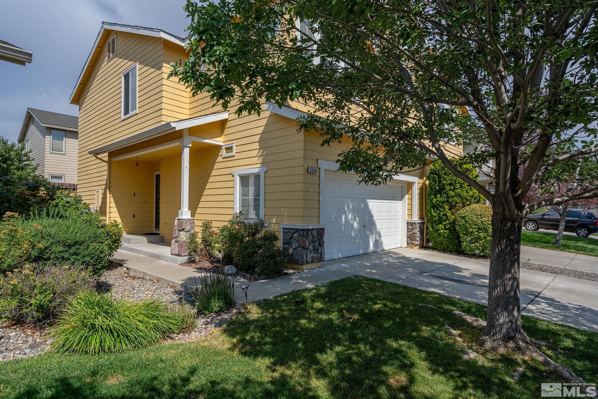 a view of a house with a small yard plants and large tree