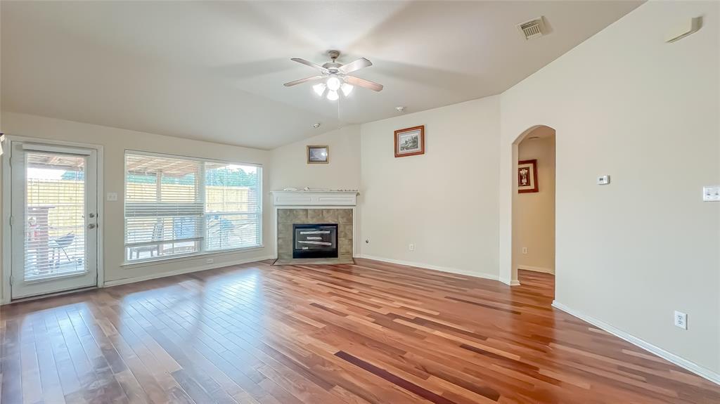 an empty room with windows fireplace and wooden floor