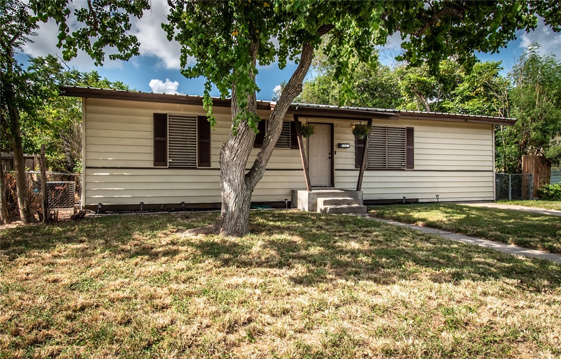 a view of a house with a yard and large tree