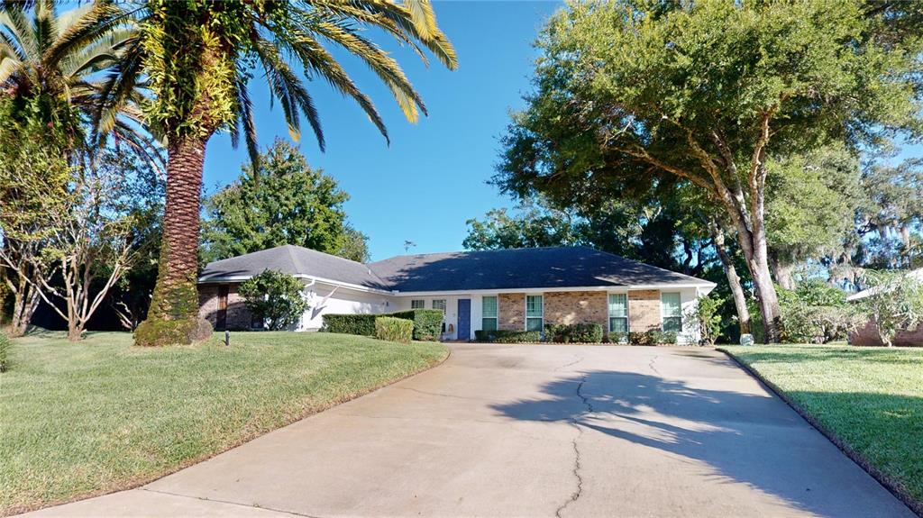 a white house with a big yard and large trees