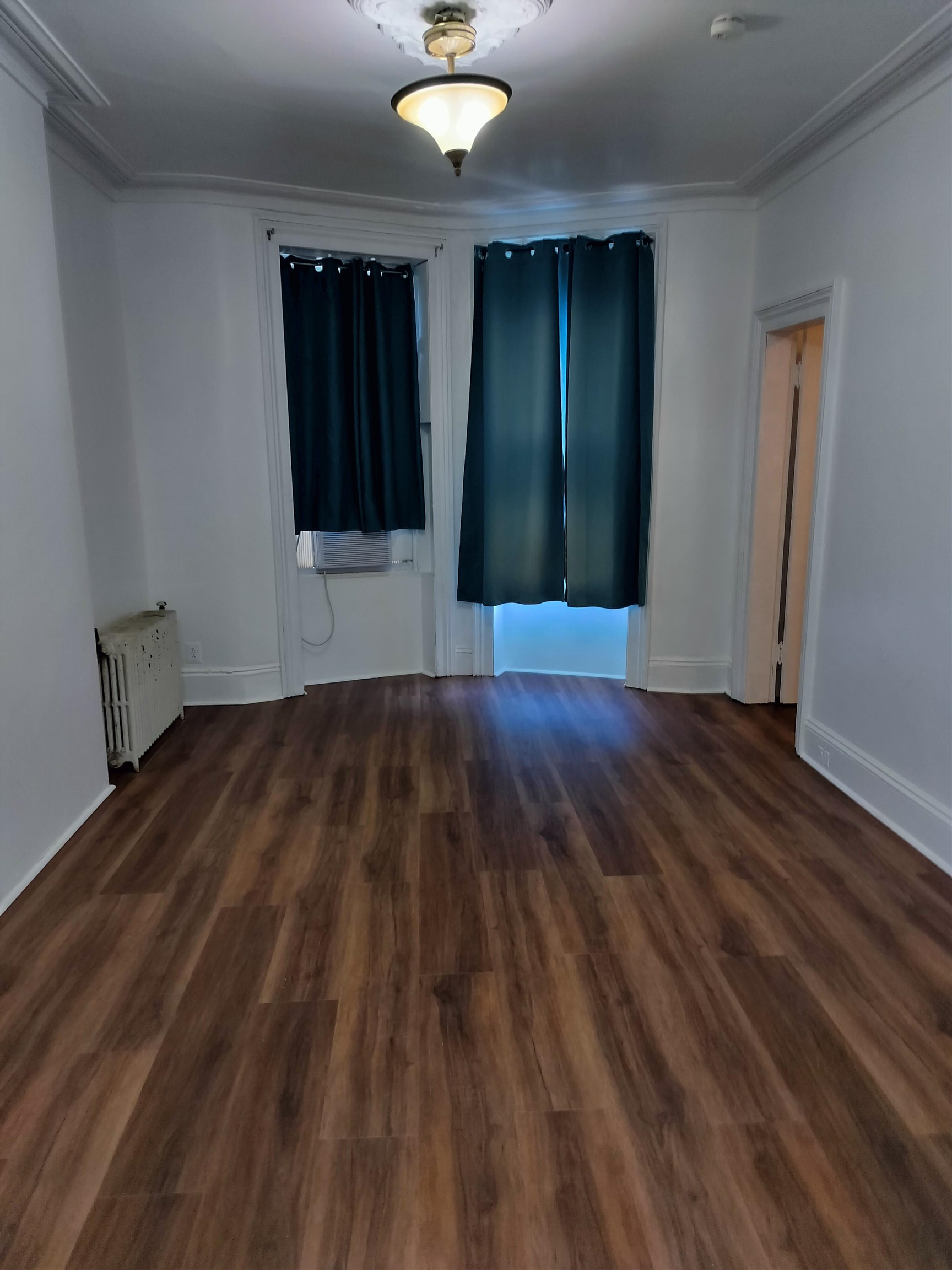 an empty room with wooden floor and windows