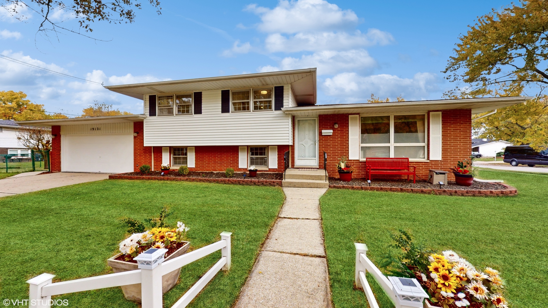 a front view of a house with garden and two chairs