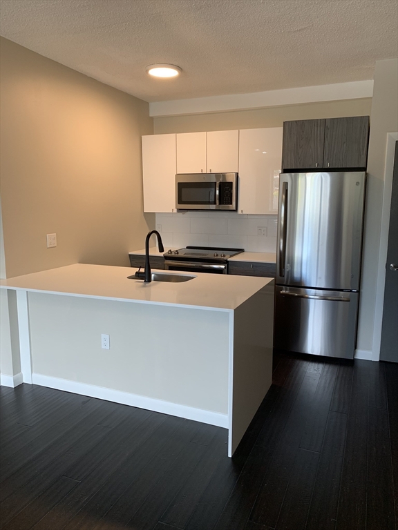 a kitchen with a sink a refrigerator and wooden floor