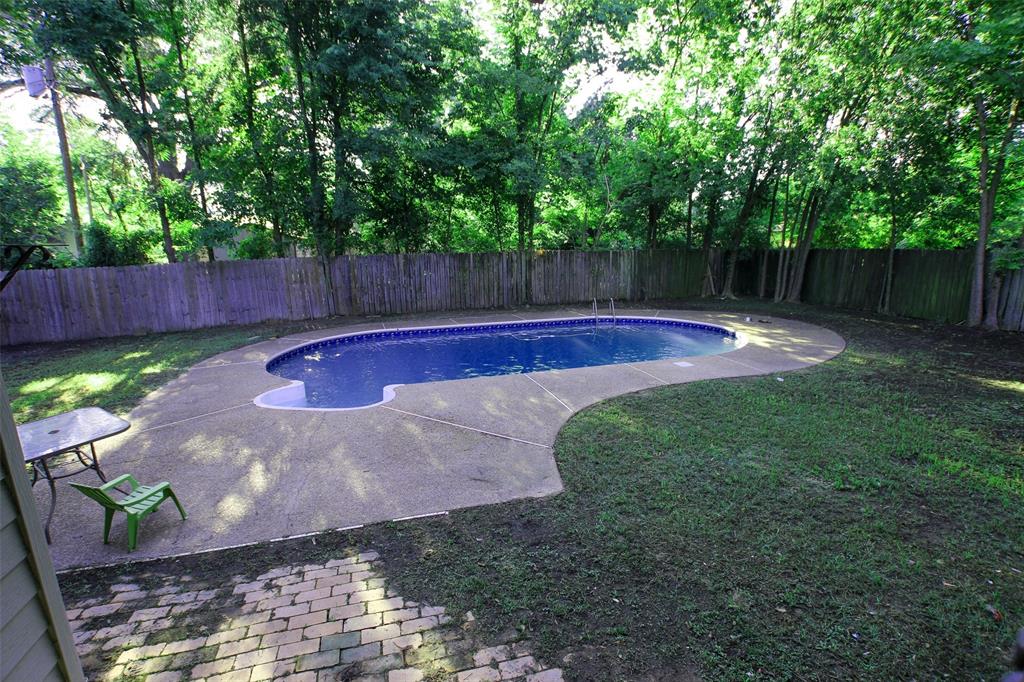 a view of a backyard with swimming pool and wooden fence