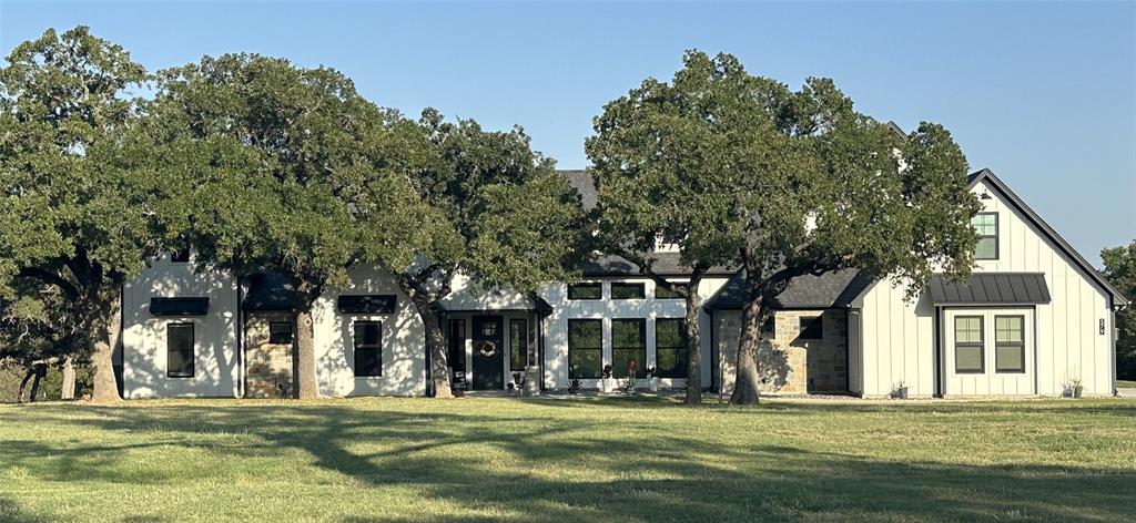 front view of a brick building with a big yard and large trees