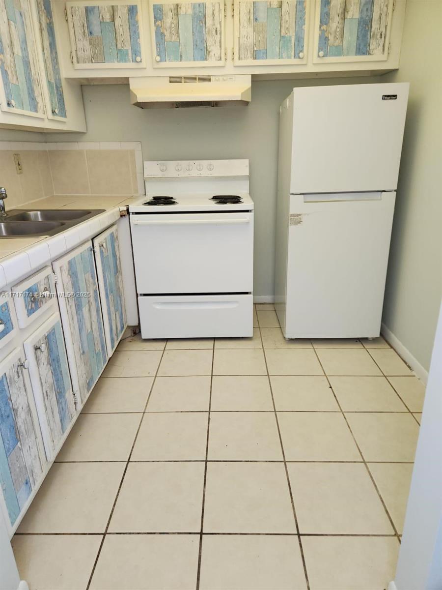 a kitchen with a stove top oven and white cabinets