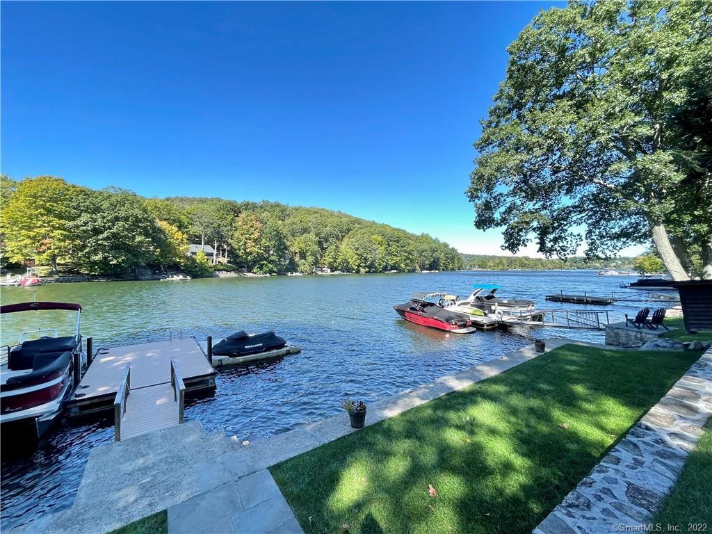 a view of a lake with couches and table and chairs under an umbrella