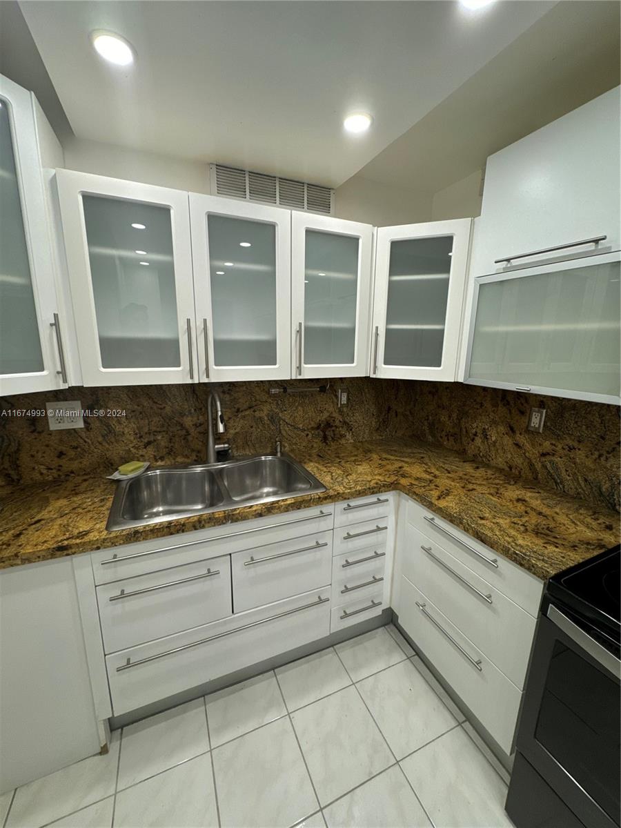 a kitchen with granite countertop white cabinets and sink