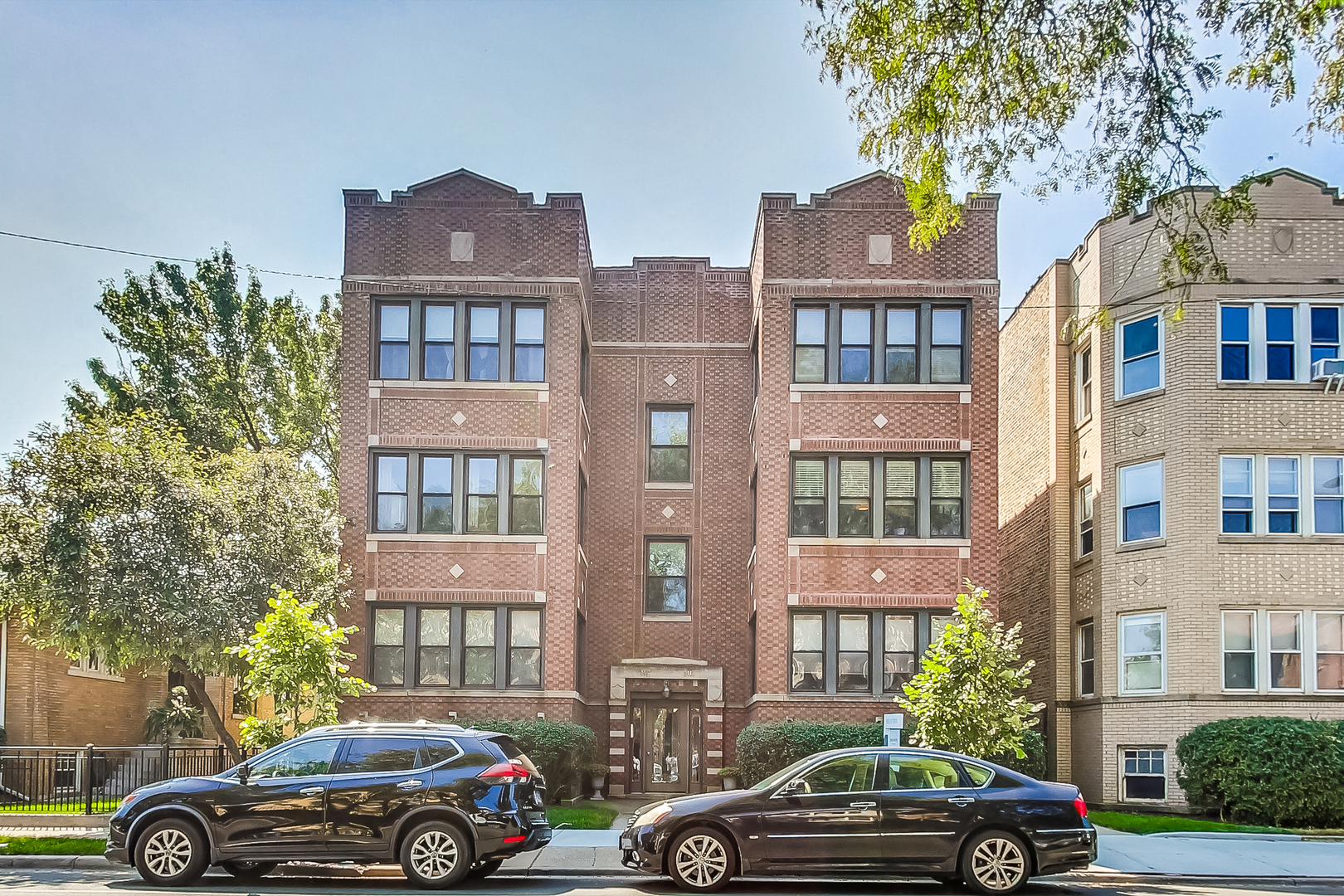 a front view of a residential apartment building with a cars parked