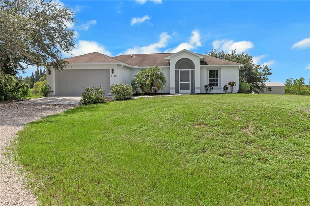 Ranch-style house featuring a garage and a front lawn