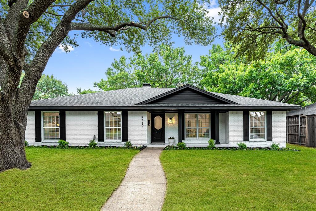 a front view of a house with a yard and green space