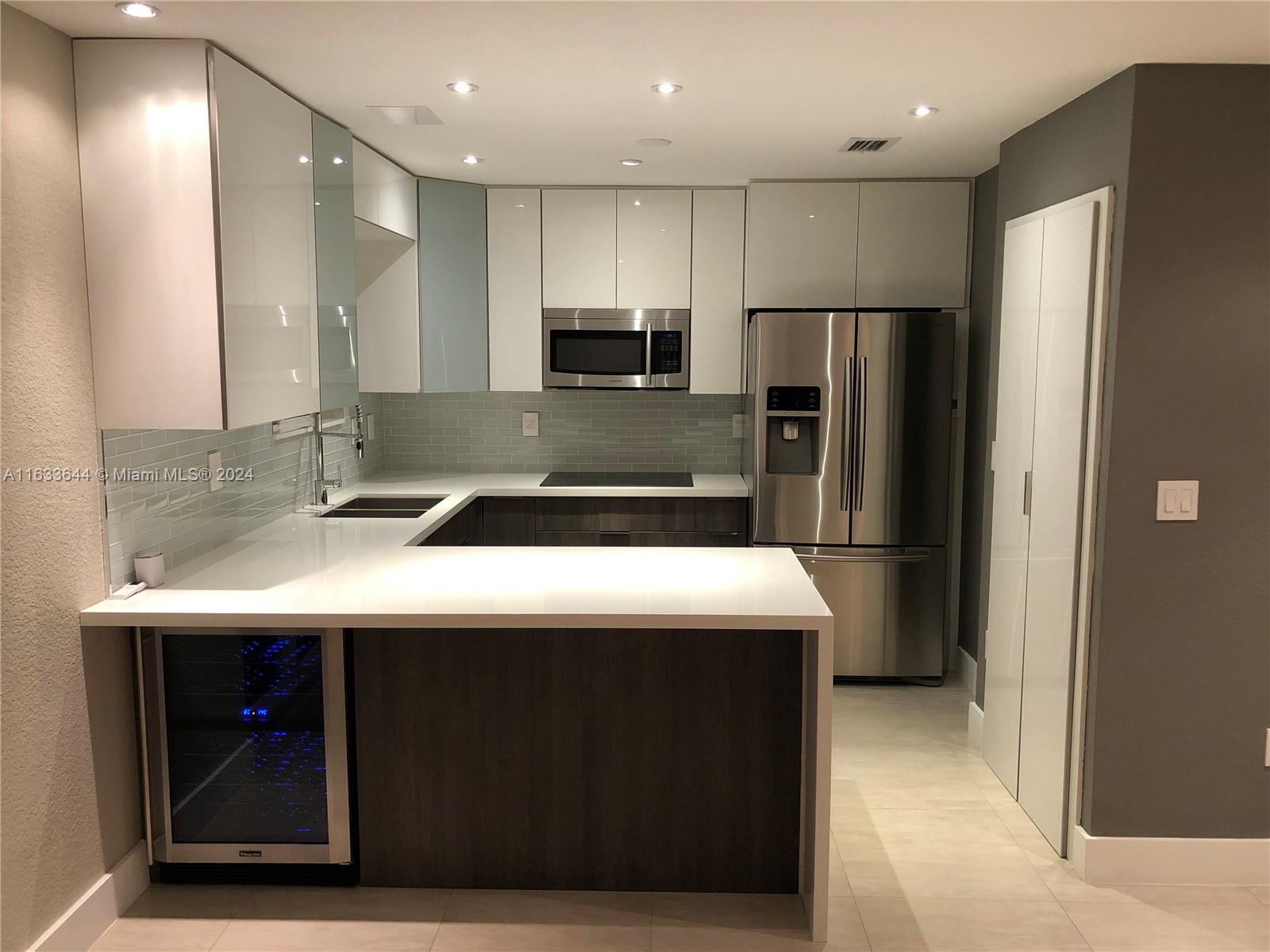 a kitchen with kitchen island stainless steel appliances a sink and refrigerator