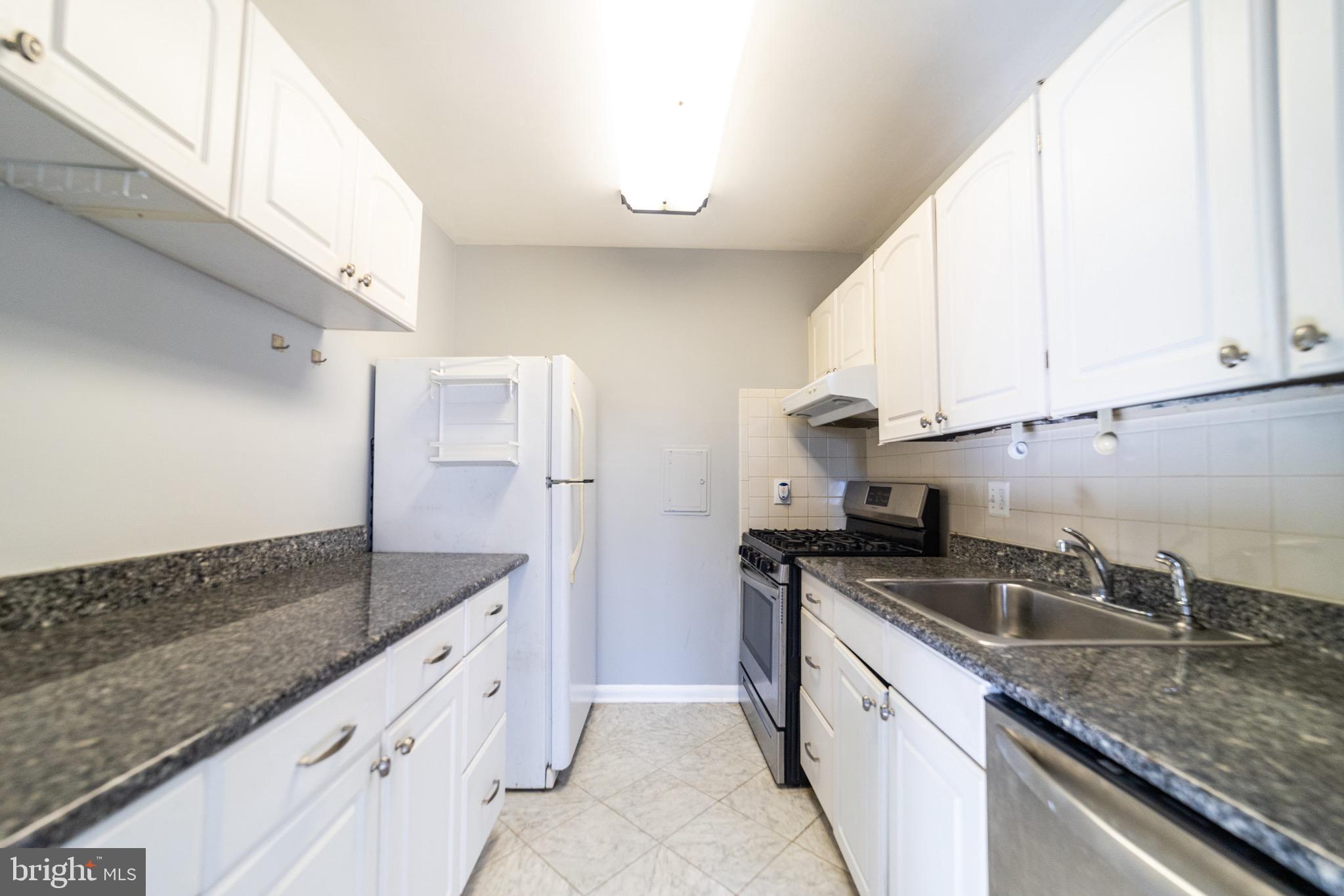 a kitchen with granite countertop white cabinets and a sink