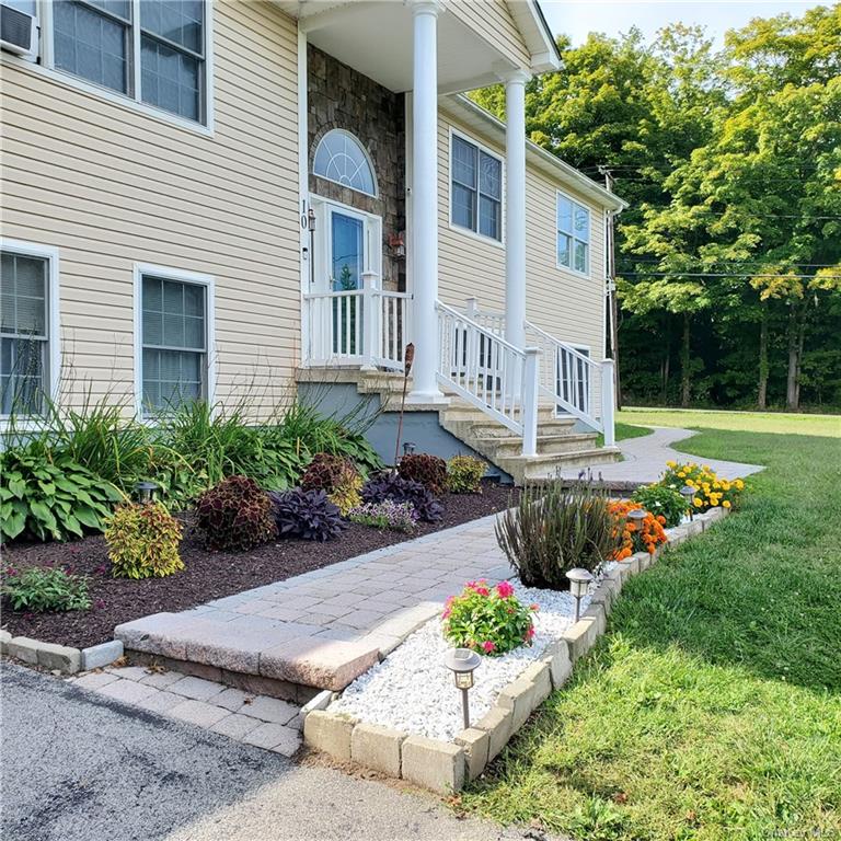 Doorway to property with a lawn and covered porch