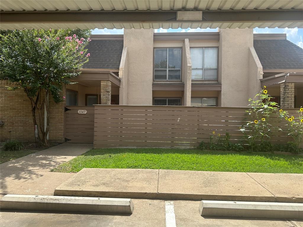 a small white building with a yard and a large window