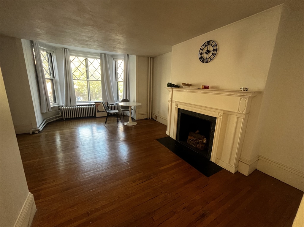 a view of an empty room with wooden floor and a fireplace