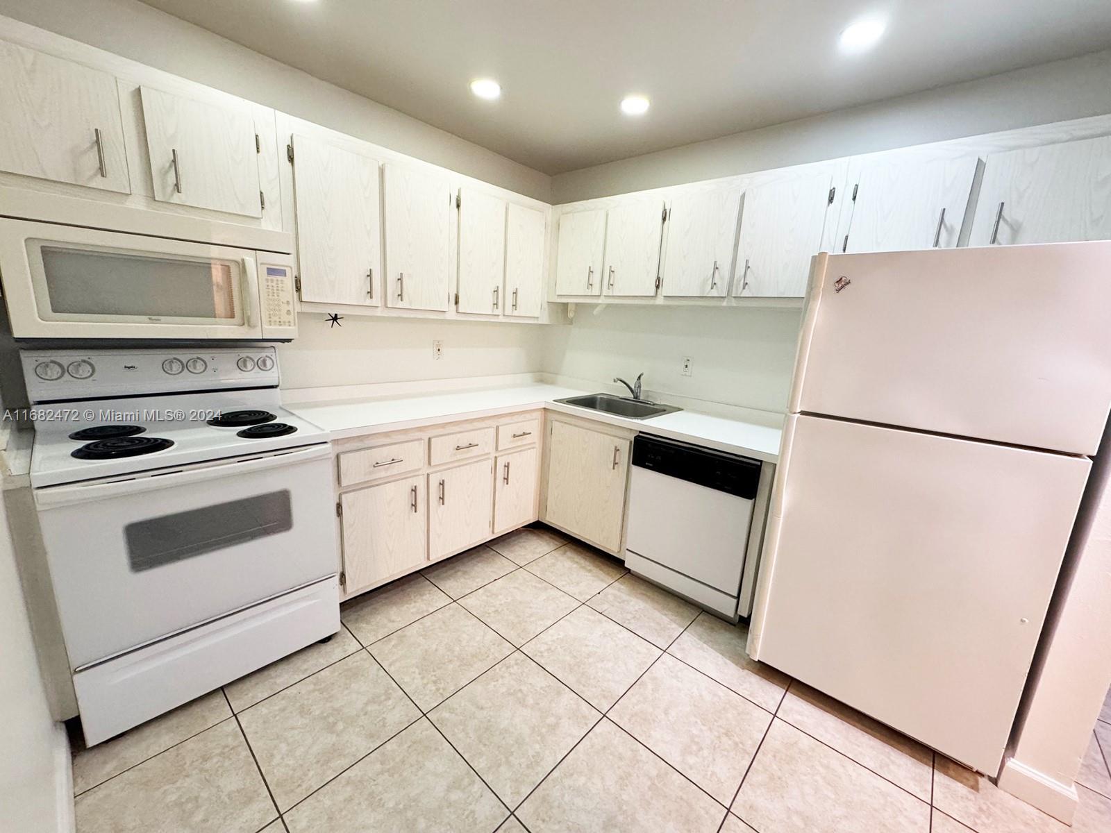 a kitchen with white cabinets and white appliances